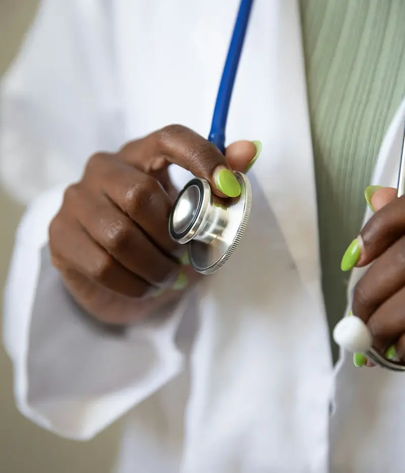A female doctor with green nail polish holds her stethoscope