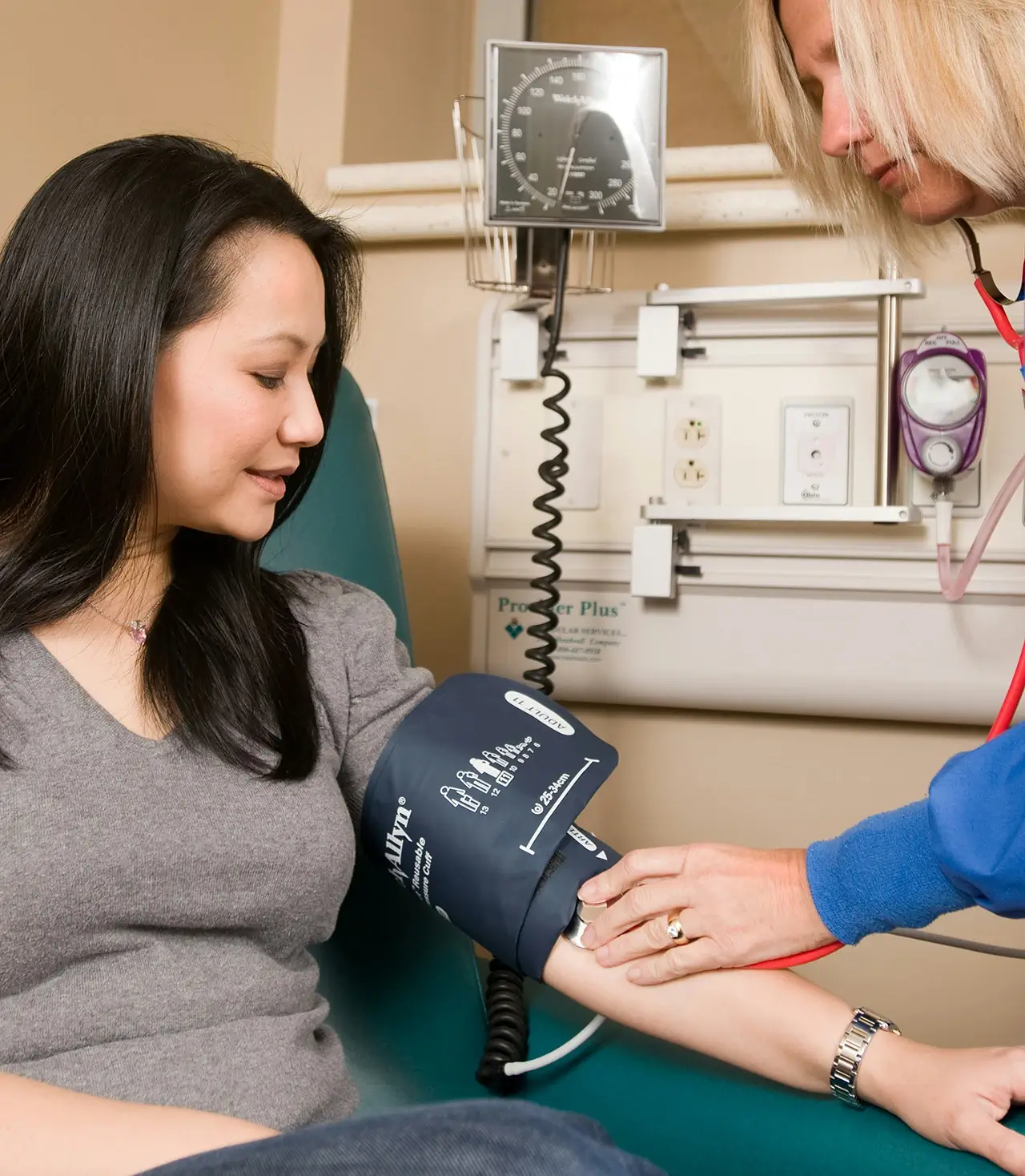 Nurse checking woman's blood pressure